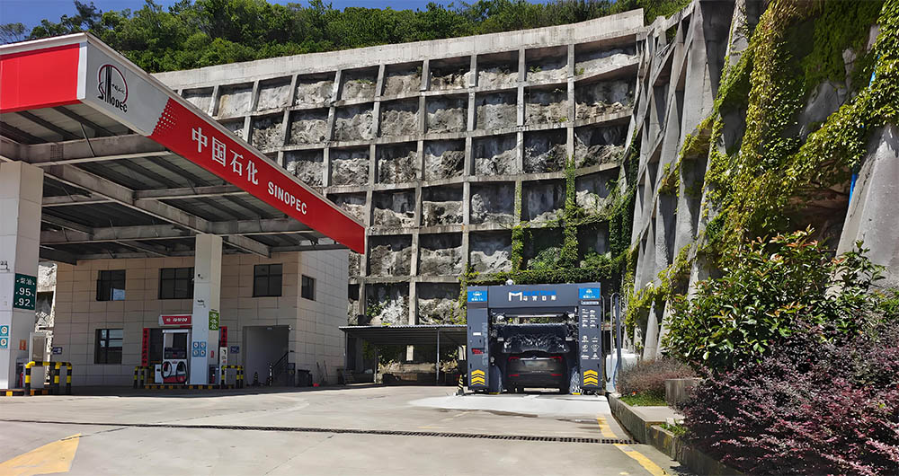 In-Bay Automatic vs. Conveyorized Tunnel Systems: Choosing the Right Car Wash for Your Business 1 A gas station with an in-bay automatic car wash system integrated near fuel pumps